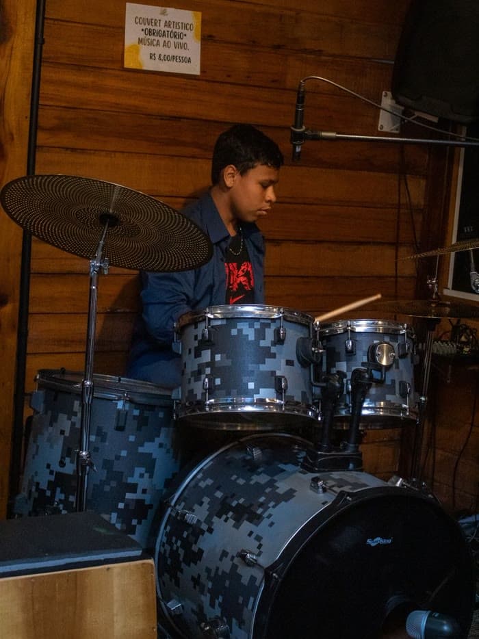Aluno concentrado tocando bateria em sala da Badrumtss