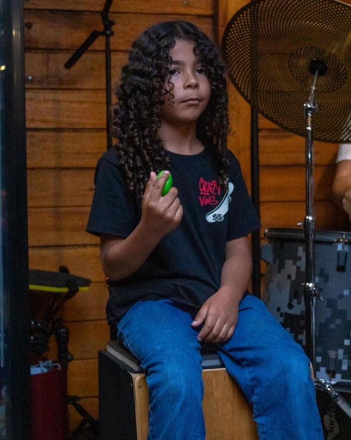 Aluno jovem com instrumento de percussão na Badrumtss
